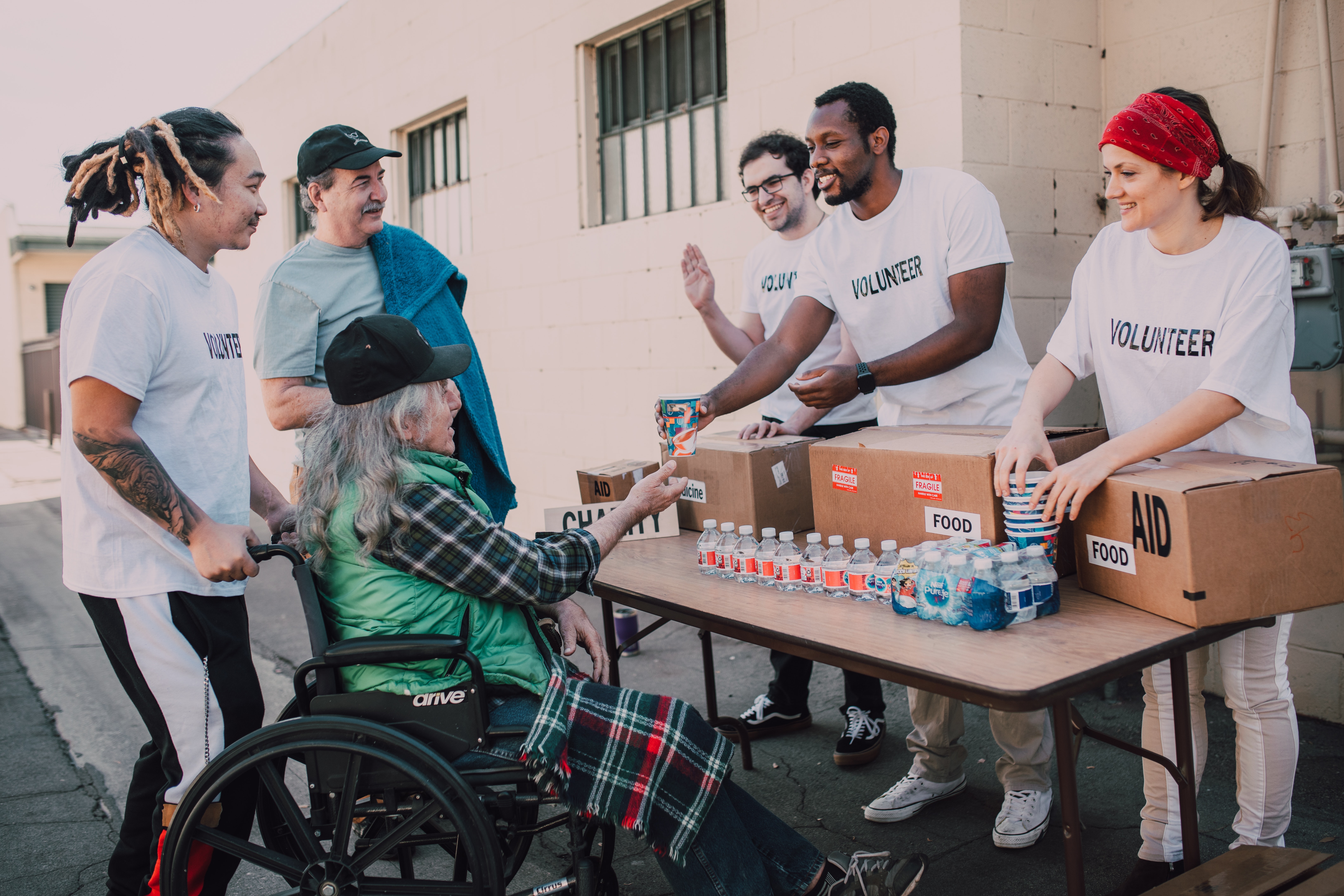 Volunteers handing out water to a person in a wheelchair